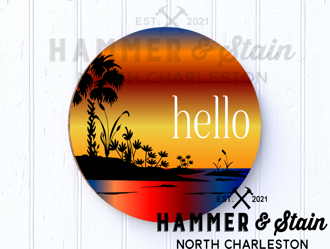 round or doorhanger with a silhouette picture of a palmetto tree and the marsh with the word hello