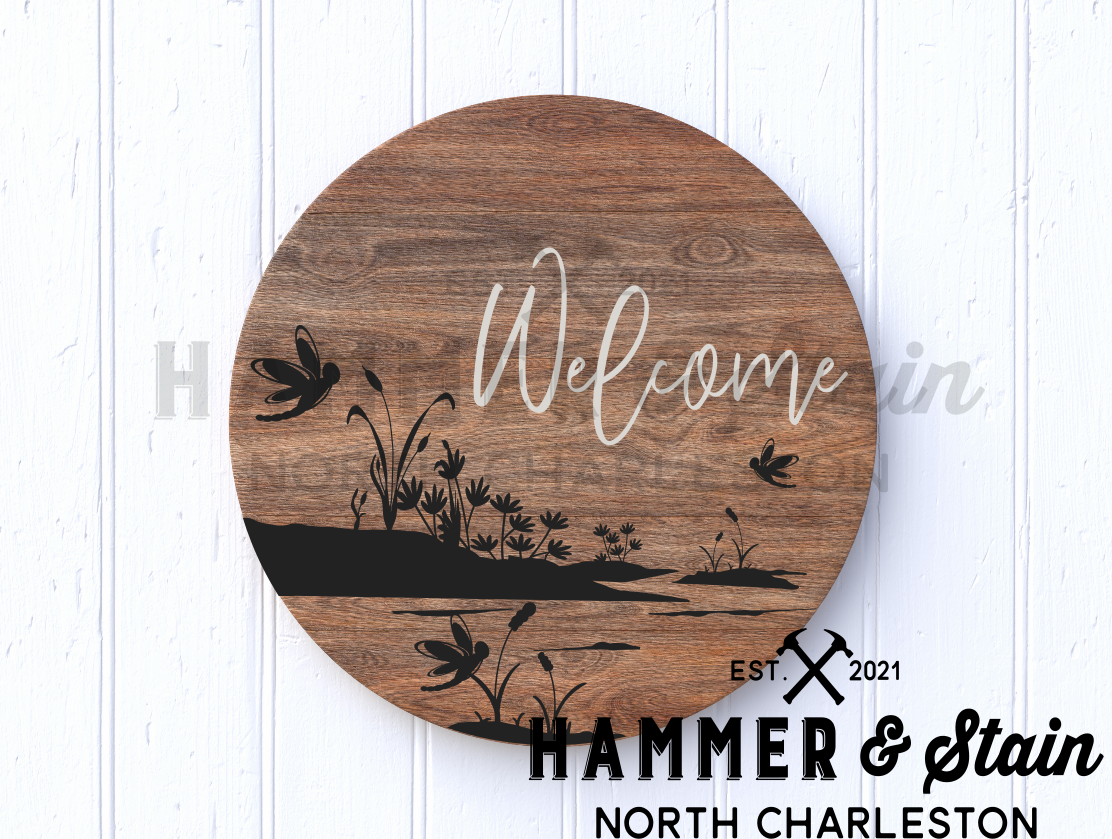 round or doorhanger with a silhouette of the marsh and dragonflies