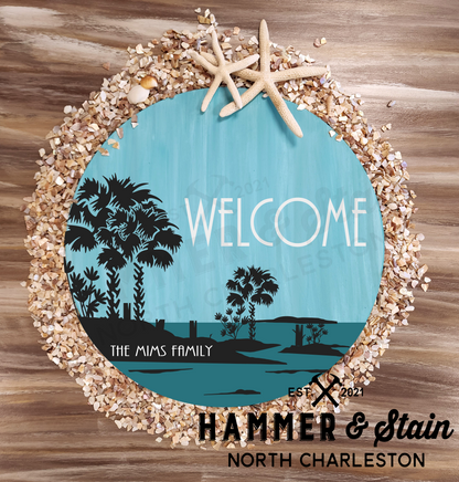 round or doorhanger with a silhouette picture of Palmetto trees, a missing dock and an island with the word welcome