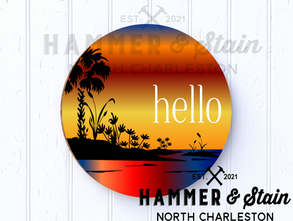 round or doorhanger with a silhouette picture of a palmetto tree and the marsh with the word hello 