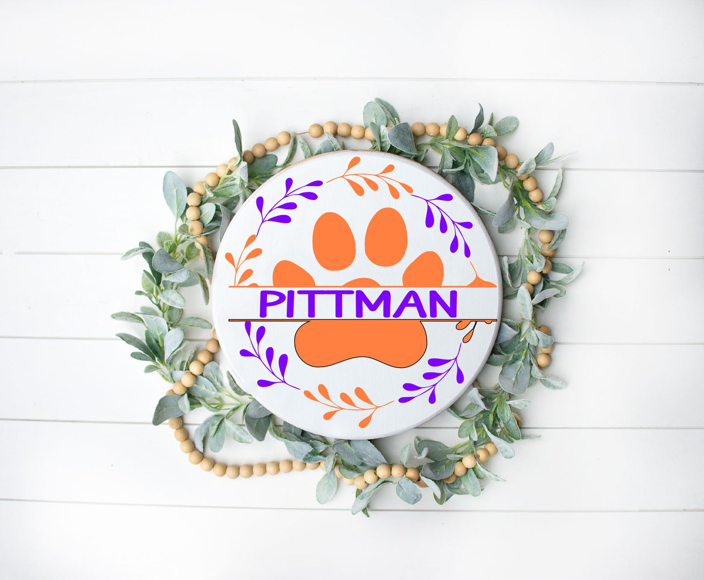 round or doorhanger with a paw print in the middle surrounded by a wreath with a last name